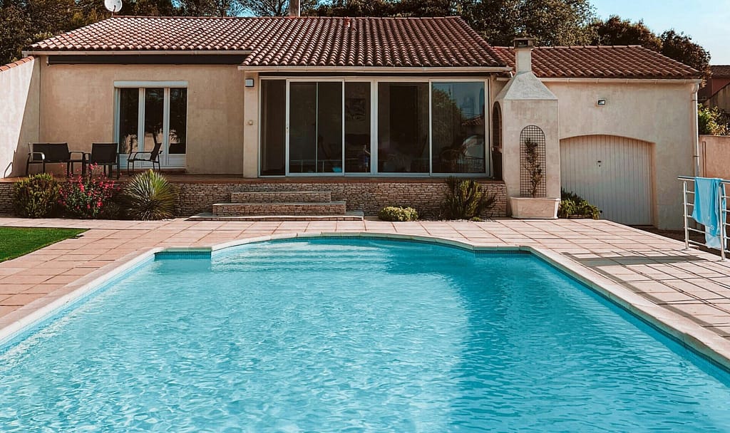 Charming suburban home with a swimming pool, set against a clear blue sky.