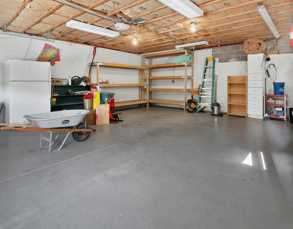 Spacious garage interior with storage shelves, tools, and a wheelbarrow, ideal for home organization.