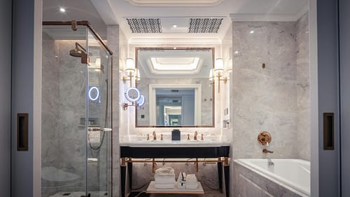 Elegant bathroom featuring a marble sink, bathtub, and mirror with ambient lighting.