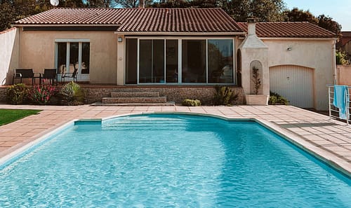 Charming suburban home with a swimming pool, set against a clear blue sky.