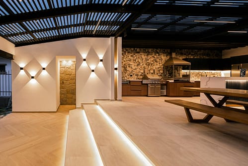 Experience a luxurious modern outdoor kitchen with sleek lighting and a sophisticated design.