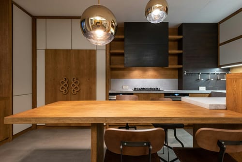 Sleek minimalist kitchen with wooden cabinetry and modern pendant lights.