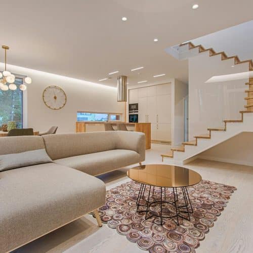 Contemporary living room with neutral tones, a sleek sofa, and elegant wooden staircase.