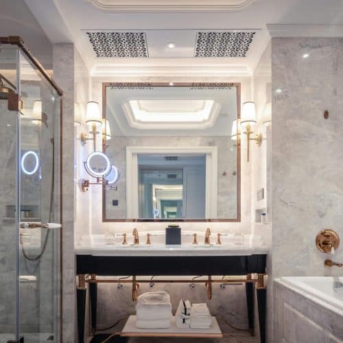 Elegant bathroom featuring a marble sink, bathtub, and mirror with ambient lighting.