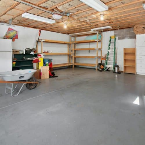 Spacious garage interior with storage shelves, tools, and a wheelbarrow, ideal for home organization.