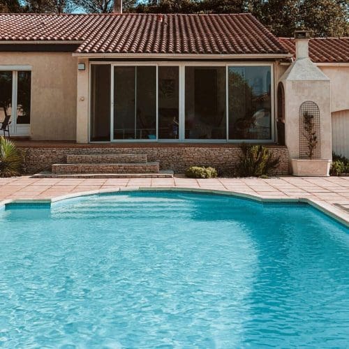 Charming suburban home with a swimming pool, set against a clear blue sky.